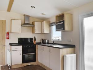 a kitchen with white cabinets and a black appliance at Meres Retreat in Saxmundham