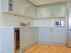 een keuken met witte kasten en een koelkast bij Merrow Cottage in Ledbury