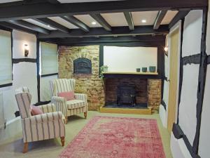 een woonkamer met 2 stoelen en een stenen open haard bij Merrow Cottage in Ledbury