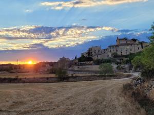 a dirt road in front of a town with the sunset at Les Cavallerisses in Guialmons