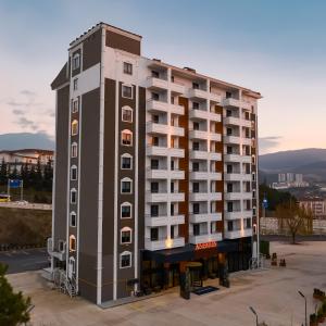 un edificio de apartamentos alto en un estacionamiento en Anemon Karabük Hotel en Karabük