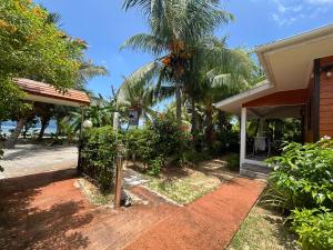 a house with a palm tree and a brick driveway at Anse Grosse Roche Beach Villa in La Digue