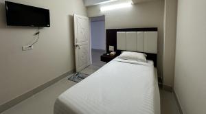ein kleines Schlafzimmer mit einem Bett und einem Flachbild-TV in der Unterkunft Hotel Kingfisher - Barishal in Barishal