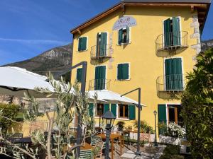 un edificio giallo con tavoli e ombrelloni di fronte di Relais Fontana Rosa B&B Wellness a Caprino Veronese