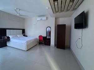 a bedroom with a bed and a flat screen tv at Hotel Kingfisher - Barishal in Barisāl
