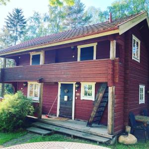 Cabaña de madera roja con porche y escalera en Villa Franca Maria en Rättvik