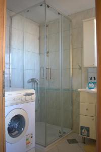 a shower with a glass door next to a washing machine at Apartman Marko in Tribunj