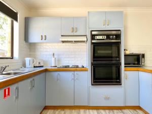 een keuken met witte kasten en zwarte apparaten bij Near Murray River - A Lovely Holiday Unit in Moama in Moama
