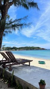 una playa con un banco y un árbol y el océano en Layla Cottage Gành Đá Đĩa, en Tuy Hoa