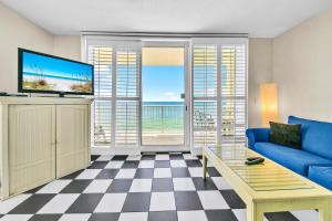 a living room with a blue couch and a tv at Majestic Beach Towers 1-1615 in Panama City Beach