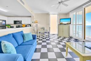 a living room with a blue couch and a kitchen at Majestic Beach Towers 1-1615 in Panama City Beach