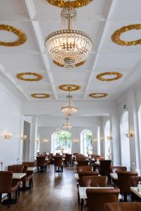 a dining room with chandeliers and tables and chairs at Milling Hotel Saxildhus in Kolding