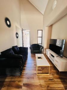 ein Wohnzimmer mit einem schwarzen Sofa und einem Couchtisch in der Unterkunft Morningside41 in Ongwediva