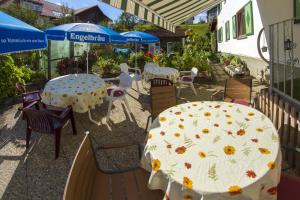 een patio met tafels, stoelen en parasols bij Landhaus Sonnwinkl in Wertach