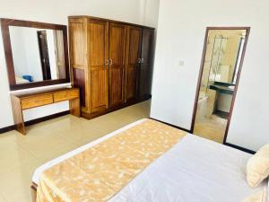 a bedroom with a bed and a dresser and a mirror at Wimbledon Two Rooms Apartment in Colombo
