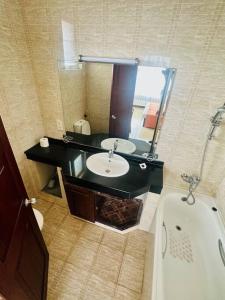 a bathroom with a sink and a mirror and a tub at Wimbledon Two Rooms Apartment in Colombo