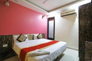 sypialnia z dużym łóżkiem z czerwoną ścianą w obiekcie Hotel Star Inn - Delhi Airport, Mahipalpur, Aerocity w Nowym Delhi