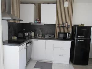 uma cozinha com armários brancos e um frigorífico preto em Appartement 3 pièces proche Disneyland em Magny-le-Hongre