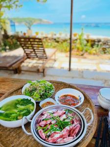 einen Tisch mit Teller mit Speisen auf einem Tisch in Strandnähe in der Unterkunft Layla Cottage Gành Đá Đĩa in Tuy Hoa