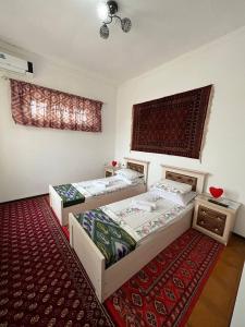 een slaapkamer met 2 bedden en een rode loper bij Hotel ISMOIL SAMONI in Bukhara