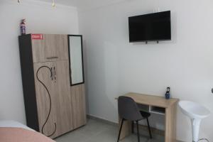 Habitación con escritorio, armario y TV. en URRR Casa on Msasa, en Randburg