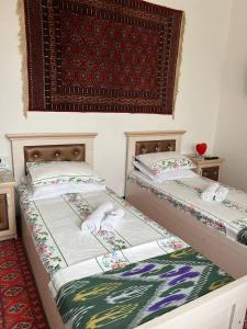 twee bedden naast elkaar in een kamer bij Hotel ISMOIL SAMONI in Bukhara