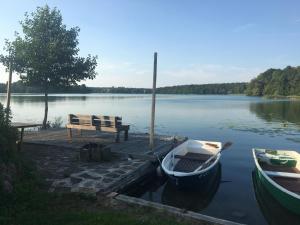 a wooden dock with a bench and a boat on a lake at Forsthaus am See Lychen in Lychen
