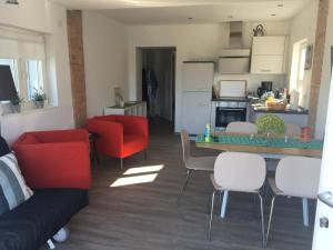 a kitchen and living room with red chairs and a table at Forsthaus am See Lychen in Lychen