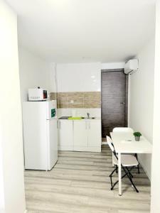 a white kitchen with a table and a white refrigerator at Apartamentos Aeropuerto Valencia in Manises