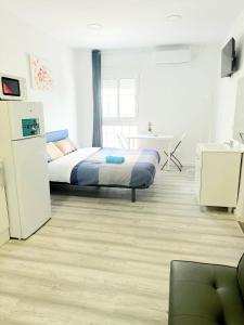 ein Schlafzimmer mit einem Bett und einem Schreibtisch sowie eine Küche in der Unterkunft Apartamentos Aeropuerto Valencia in Manises