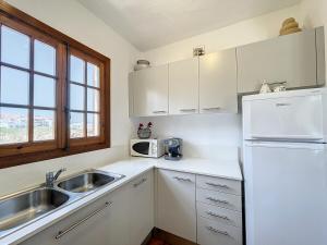 uma cozinha com um lavatório e um frigorífico branco em P107 Un rinconcito en el mar em Fornells