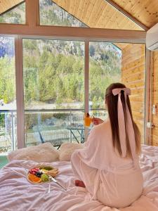 a woman sitting on a bed with a plate of food at Guesthouse Marashi in Theth