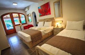 a bedroom with two beds and a red chair at Aquamarine Apartments in Paleo Tsifliki