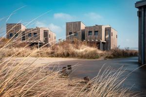dos edificios en una playa con césped alto en Studio Deluxe 2 Pers Punt West - Land view - Ouddorp, en Ouddorp