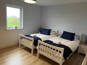 two twin beds in a room with a window at Tunstall Farm Cottage in Tunstall