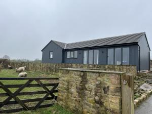 a black house with a stone wall and a fence at Tunstall Farm Cottage in Tunstall