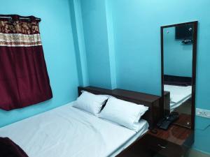 ein blaues Zimmer mit einem Bett und einem Spiegel in der Unterkunft Hotel Ambika in Deoghar