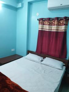 a bed in a room with a red curtain at Hotel Ambika in Deoghar