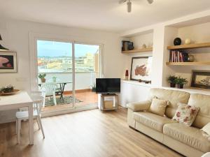 ein Wohnzimmer mit einem Sofa, einem TV und einem Tisch in der Unterkunft Ancora Apartment in Vilanova i la Geltrú