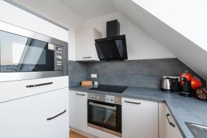 a white kitchen with a microwave and a stove at SYMPHONY Apartments 39 - Modern Loft with Terrace and Grill in Central Location in Vienna