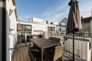 a balcony with a wooden table and chairs and an umbrella at SYMPHONY Apartments 39 - Modern Loft with Terrace and Grill in Central Location in Vienna