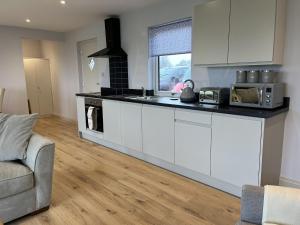 a kitchen with white cabinets and a counter top at Fleetwood 2 bed cottage in Tunstall +8 photos