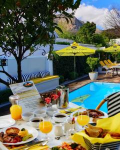 a table with food and drinks next to a swimming pool at Fleur du Soleil Luxury Guesthouse in Franschhoek