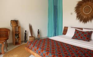 a bedroom with a bed with a colorful blanket on it at Aurora Boutique Hotel Jambiani in Jambiani