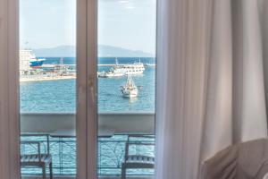 Blick auf ein Boot im Wasser aus einem Fenster in der Unterkunft Lesvion Hotel in Mytilini