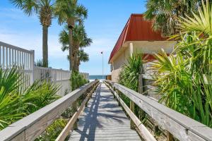a wooden walkway leading to a beach with palm trees at Misty Harbour 7 in Panama City Beach