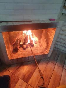 a fireplace with a stick in it with flames at Chalé alpino mobiliado perto do centro de canela rs in Canela