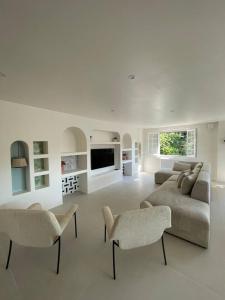 sala de estar blanca con sofá y sillas en Villa de 5 chambres avec piscine privee jardin clos et wifi a Saint Sulpice de Royan a 6 km de la plage, en Saint-Sulpice-de-Royan
