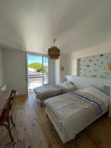 1 dormitorio con 2 camas y balcón en Villa de 5 chambres avec piscine privee jardin clos et wifi a Saint Sulpice de Royan a 6 km de la plage, en Saint-Sulpice-de-Royan