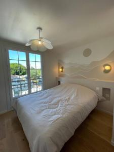 1 cama blanca en un dormitorio con ventana grande en Villa de 5 chambres avec piscine privee jardin clos et wifi a Saint Sulpice de Royan a 6 km de la plage, en Saint-Sulpice-de-Royan